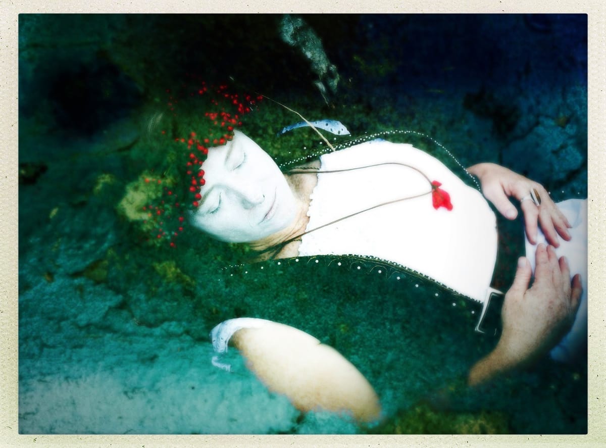 Image of Huia, pale faced as if dead, merging with the landscape a photograph she entitled "Initiation"